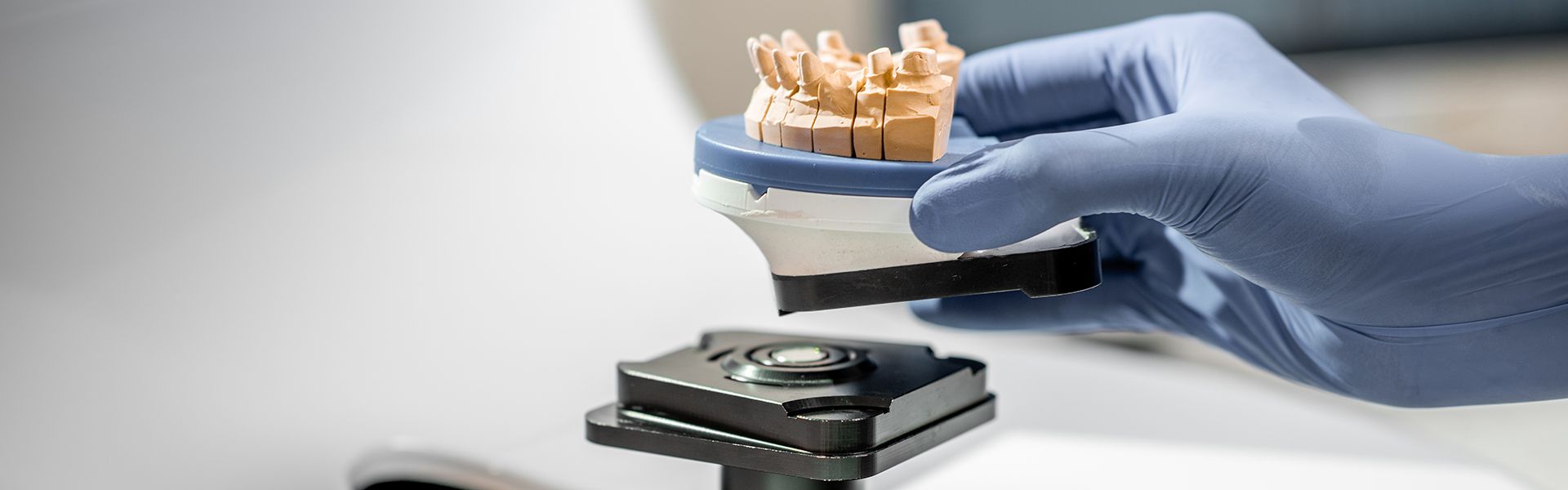 Primer plano de un técnico dental colocando el modelo de mandíbula en el escáner 3d en el laboratorio.